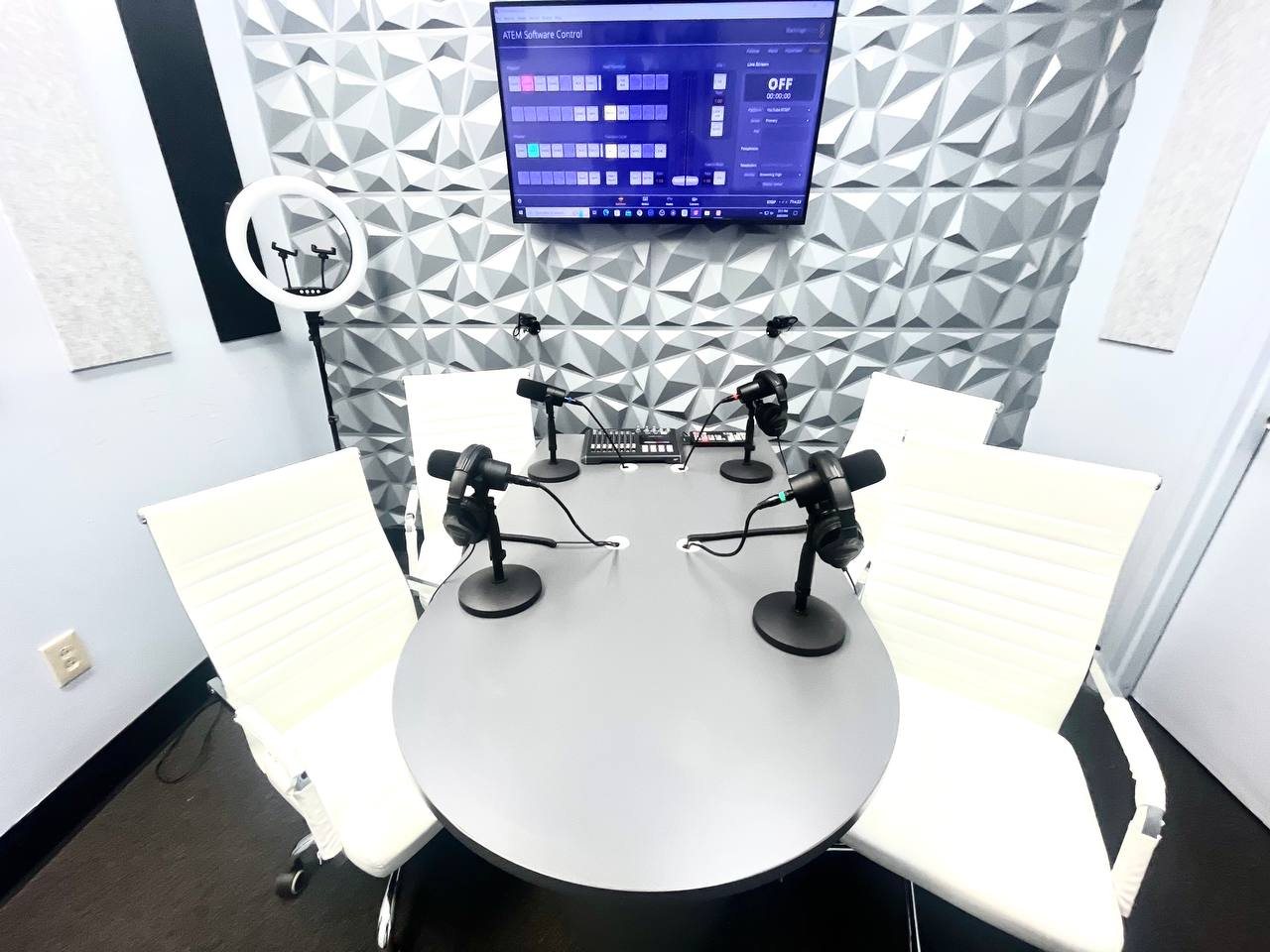The live room set for four guests with broadcast microphones and an acoustic treated wall
